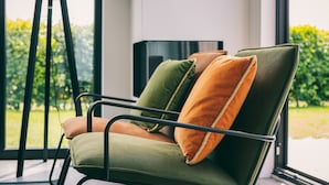 Ein moderner Stuhl mit Metallgestell und Kissen in Grün, Orange und Braun.