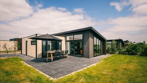 A modern house with a patio area, a dining table, and chairs.