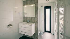 Ein modernes Badezimmer mit einem weißen Waschtisch, einem großen Spiegel und einem Toilettenpapierhalter.