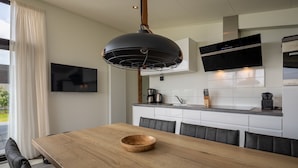 Eine moderne Küche mit einer großen Kochinsel, einem Esstisch mit einer Holzkolle und einem an der Wand montierten Fernseher.