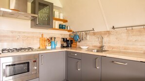 A modern kitchen with grey cabinets, a stainless steel stove, a microwave, and a sink.