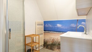 A bathroom with a beach view, a white sink, and a wooden shelf.