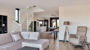 Un salon moderne avec un escalier, un coin repas et une cuisine.