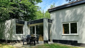 Uma casa moderna com área de pátio, mesa e cadeiras, janelas amplas e fachada de tijolo.