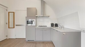 Une cuisine moderne équipée d’un four encastré, d’un four à micro-ondes, d’une cuisinière à gaz et d’une machine à café.