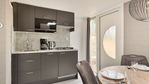 Une cuisine moderne avec des meubles de couleur sombre, un four à micro-ondes encastré, une machine à café et une cuisinière à gaz.