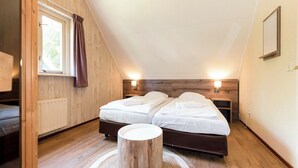 Un dormitorio ático acogedor con dos camas, paredes de madera, un ventanal con cortinas y lámparas de noche.