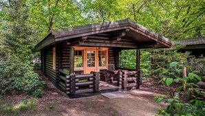 Ein rustikales Blockhaus mit einer Holzveranda und einer Tür mit Glassfeldern.
