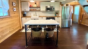 A modern kitchen with wooden walls, white cabinets, stainless steel appliances, and a central island.