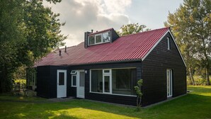 A black wooden house with a red roof, white doors, and large windows. - Semi-detached 6-person bungalow (Midlaren)