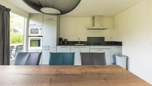 A compact kitchen with a dining table, chairs, and a view through the window. - Semi-detached 6-person bungalow (Midlaren)