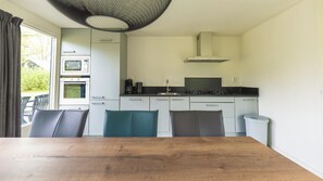 A compact kitchen with a dining table, chairs, and a view through the window.