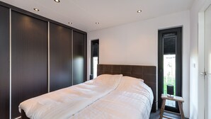 Une chambre avec un grand lit, une armoire en bois sombre et une fenêtre donnant sur un paysage verdoyant.