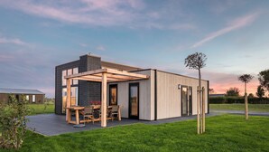 Une maison moderne dotée d’un patio, d’une table à manger et de chaises.