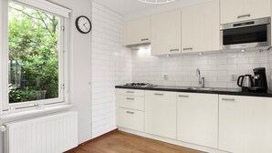 A modern kitchen with white cabinets, a black countertop, a built-in microwave, and a window with greenery outside. - Comfortable bungalow for 6 people (Diessen-Baarschot)
