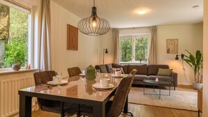 A dining area with a table set for four, a sofa, and a coffee table. - Comfortable bungalow for 4 persons (Diessen)