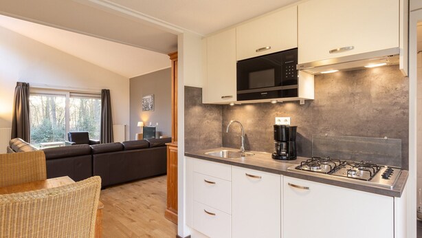 A modern kitchen with white cabinets, a black microwave, a coffee maker, and a gas stove.
