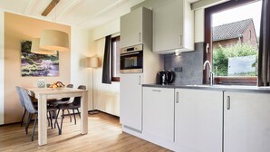 Cozinha moderna com área de refeições, apresentando uma mesa de madeira, cadeiras e um quadro na parede.