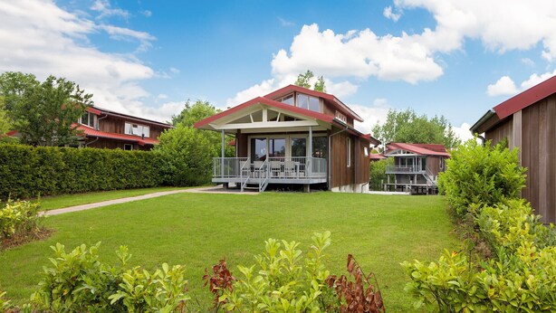 Ett modernt hus i två våningar med en täckt uteplats och en välskött gräsmatta.