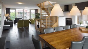 En modern inredning med ett matbord i trä, grå klädda stolar, en trappa och ett köksområde.