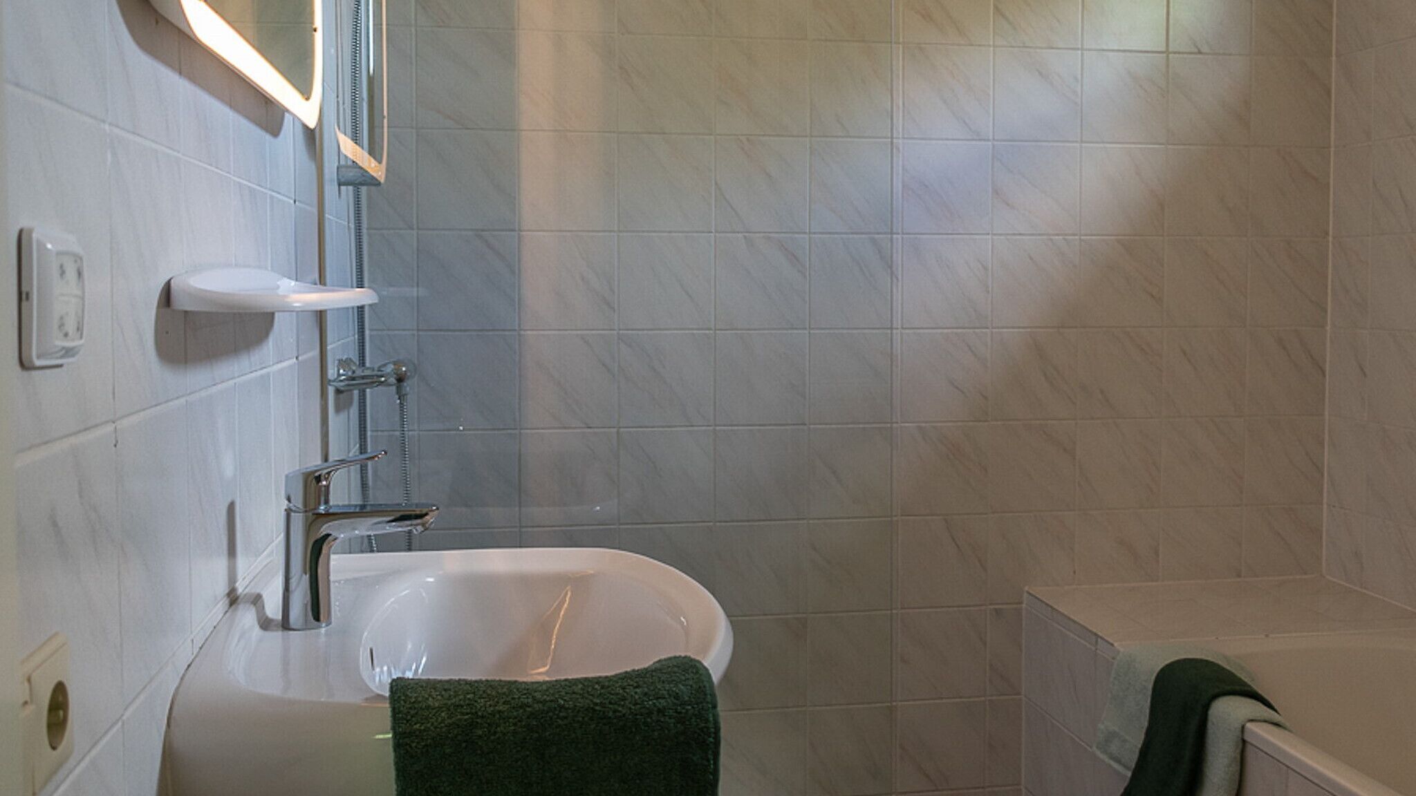 Une salle de bain avec une baignoire, un lavabo et un miroir.