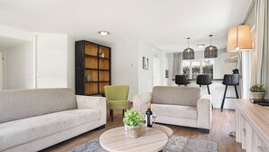 Un salon moderne comprenant un canapé, des fauteuils, une table basse et une bibliothèque.