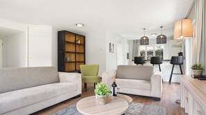 Una sala de estar moderna con un sofá, sillones, una mesa de centro y una estantería.