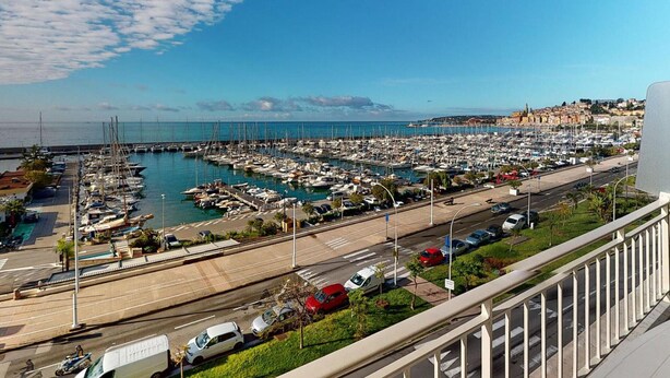 Un port esportiu amb vaixells, una carretera i un poble al capdamunt.