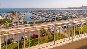 Un port esportiu amb nombroses embarcacions amarrades, un cel serè i un paisatge urbà a la distància.
