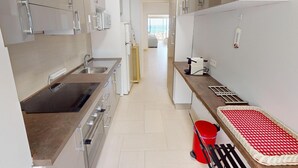 Una cuina moderna amb electrodomèstics d'acer inoxidable, forn integrat i un mantell de taula vermell i blanc a la barra.