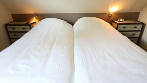 A double bed with a wooden headboard and two bedside tables with lamps. - Comfortable detached or semi-detached bungalow for 6 persons (Vlagtwedde)