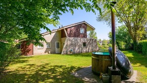 Ein zweistöckiges Haus mit Backsteinfassade, einer Holzterrasse und einem Swimmingpool.