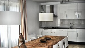 Eine moderne Küche mit Holztisch, weißen Stühlen und einer Pendelleuchte.