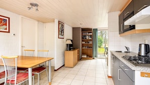 Una cocina compacta con zona de comedor, una estantería y vistas al exterior.