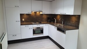 Una cocina moderna con armarios blancos, electrodomésticos de acero inoxidable y encimera negra.