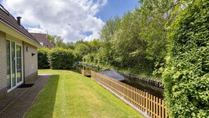 A well-maintained garden with a wooden fence, a brick pathway, and a house with a tiled roof.
