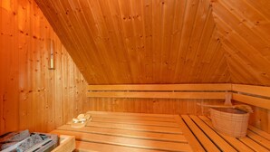 A wooden sauna with benches and a wooden bucket.