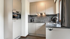 Cozinha moderna com forno embutido, chaleira e pia com torneira.