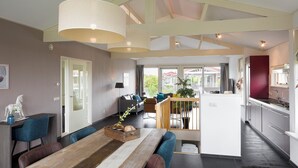Une cuisine moderne dotée d’une cuisinière intégrée et d’un coin repas avec une table en bois et des chaises bleues.