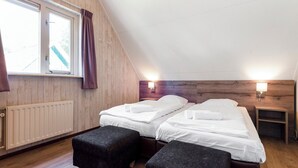 A room with two beds, a window with curtains, a radiator, and two wall-mounted lights. - Comfortable bungalow for 4 persons (Diessen-Baarschot)