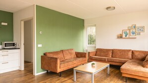 A living room with two brown leather sofas, a wooden coffee table, and a white cabinet. - Detached bungalow for 14 persons (Vlagtwedde)