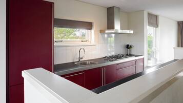 Een koffiezetapparaat/waterkoker, kookgerei, borden en bestek, eettafels