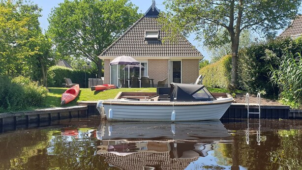 A canal with a house and a boat docked.