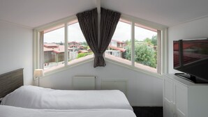 Une chambre d’hôtel avec une grande fenêtre, un lit, une télévision et un radiateur.