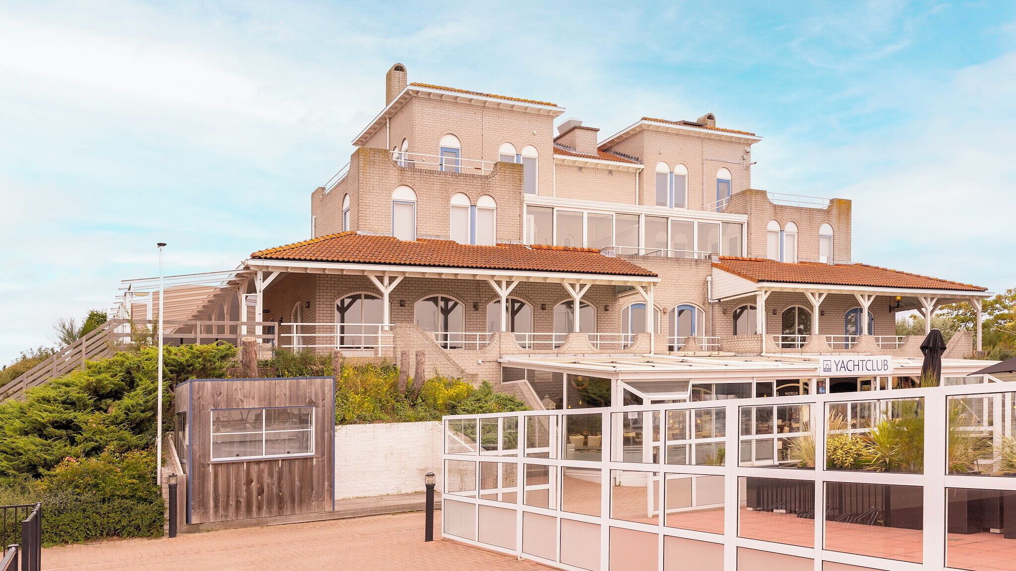 A large, historic building with multiple balconies and a covered outdoor area, likely a yacht club.