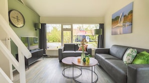 A modern living room with a grey sofa, a coffee table, and a TV on a stand.