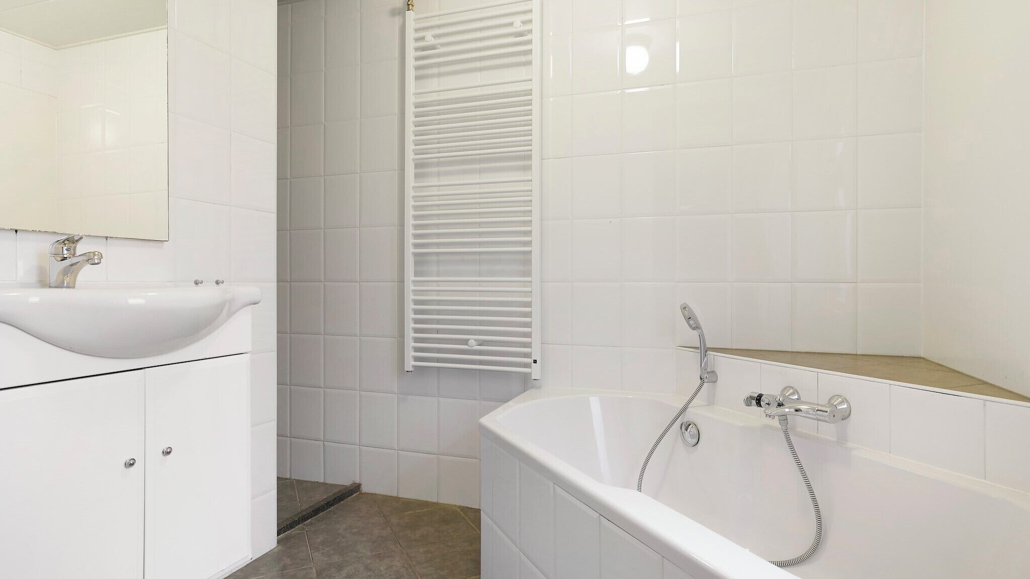 Ein Badezimmer mit einem weißen Waschbecken, einer Badewanne mit Duschbrause und einem Handtuchhalter.