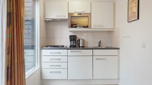 A modern kitchen with white cabinets, a gas stove, a coffee maker, and a sink.