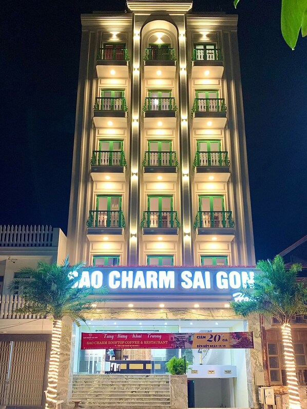 Un immeuble à plusieurs étages, doté de balcons et d’une enseigne sur laquelle on peut lire « AO CHARM SAI GON ».