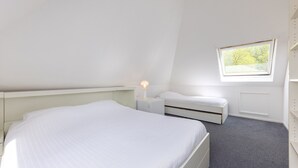 A bedroom with a bed, a bedside table, a lamp, a window, and a radiator. - Detached bungalow for 8 persons (Eernewoude)